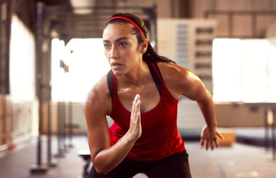 Woman at gym, moving her arms forward and back.