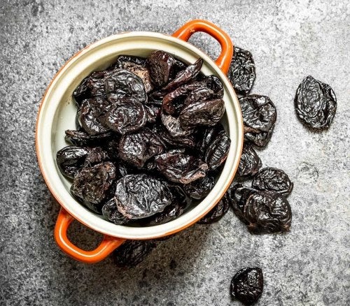 Orange cup filled with brown, black prunes.