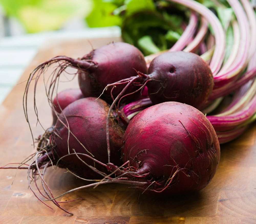 Four purple beets on a table.