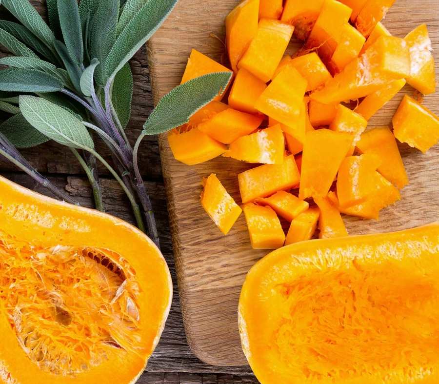 Yellow butternut squash havles and cubes on cutting board.