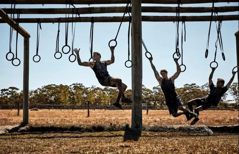Military members swinging from rings.