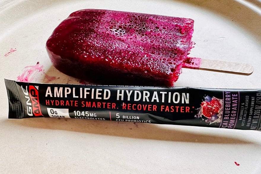 A purple popsicle next to a hydration GNC Amplified electrolyte packet.