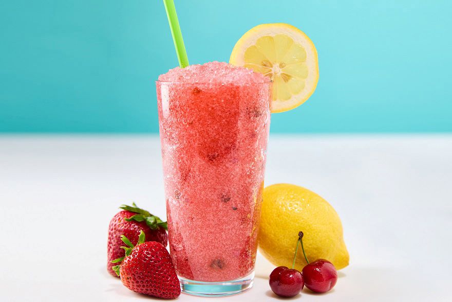 Red Berry Lemondade drink with strawberries, cherries and a lemon nect to it.