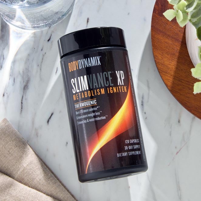 Black and orange bottle of Slimvance XP on marble table.